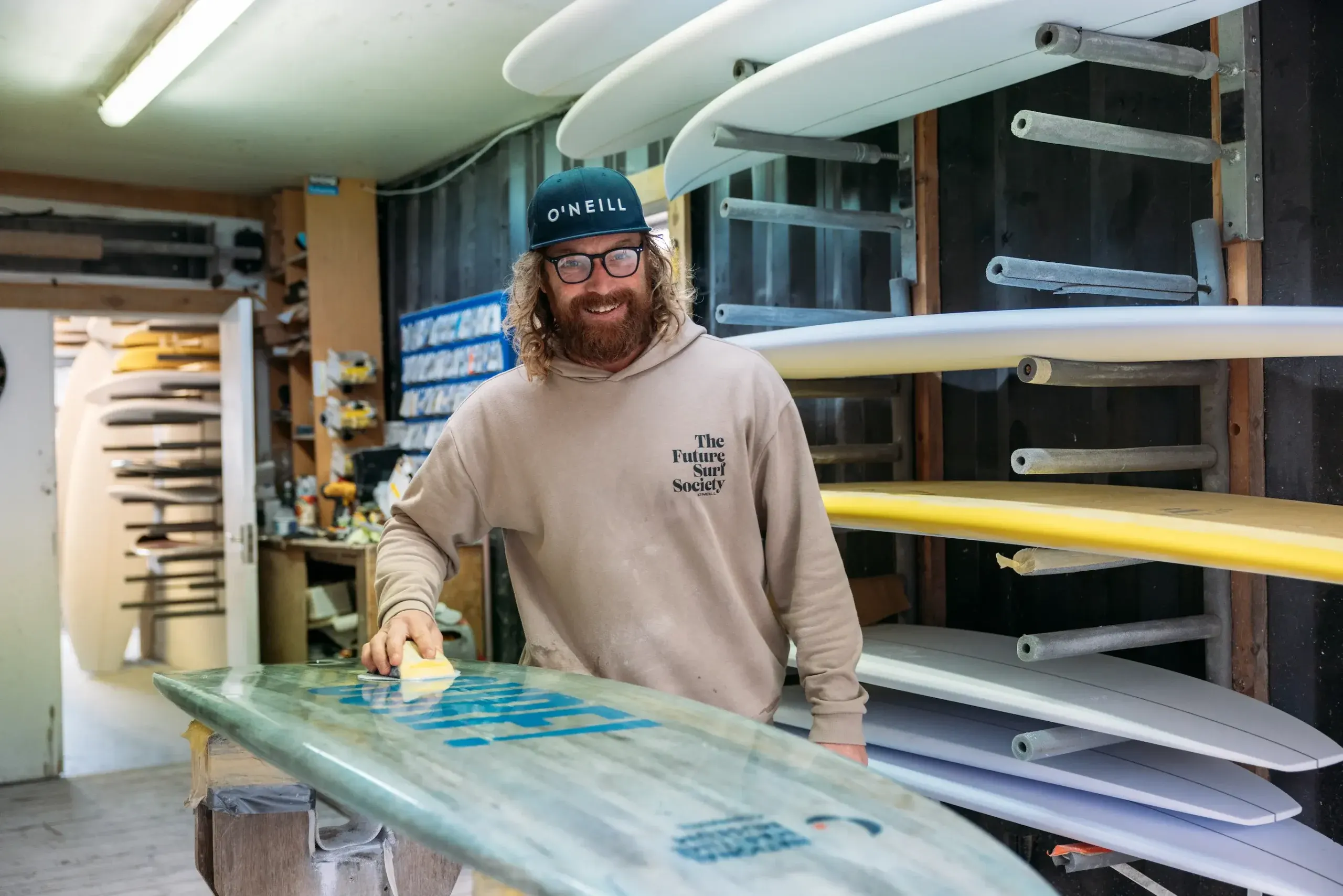 Surfboard shaper Ben Skinner polishing a board at Skindog Surfboards workshop, filmed for the National Maritime Museum Cornwall SURF exhibition